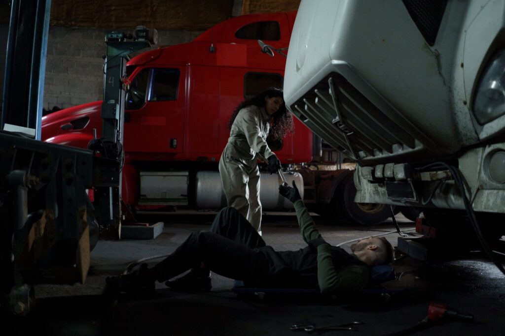 Mechanics working under a semi truck in a repair shop